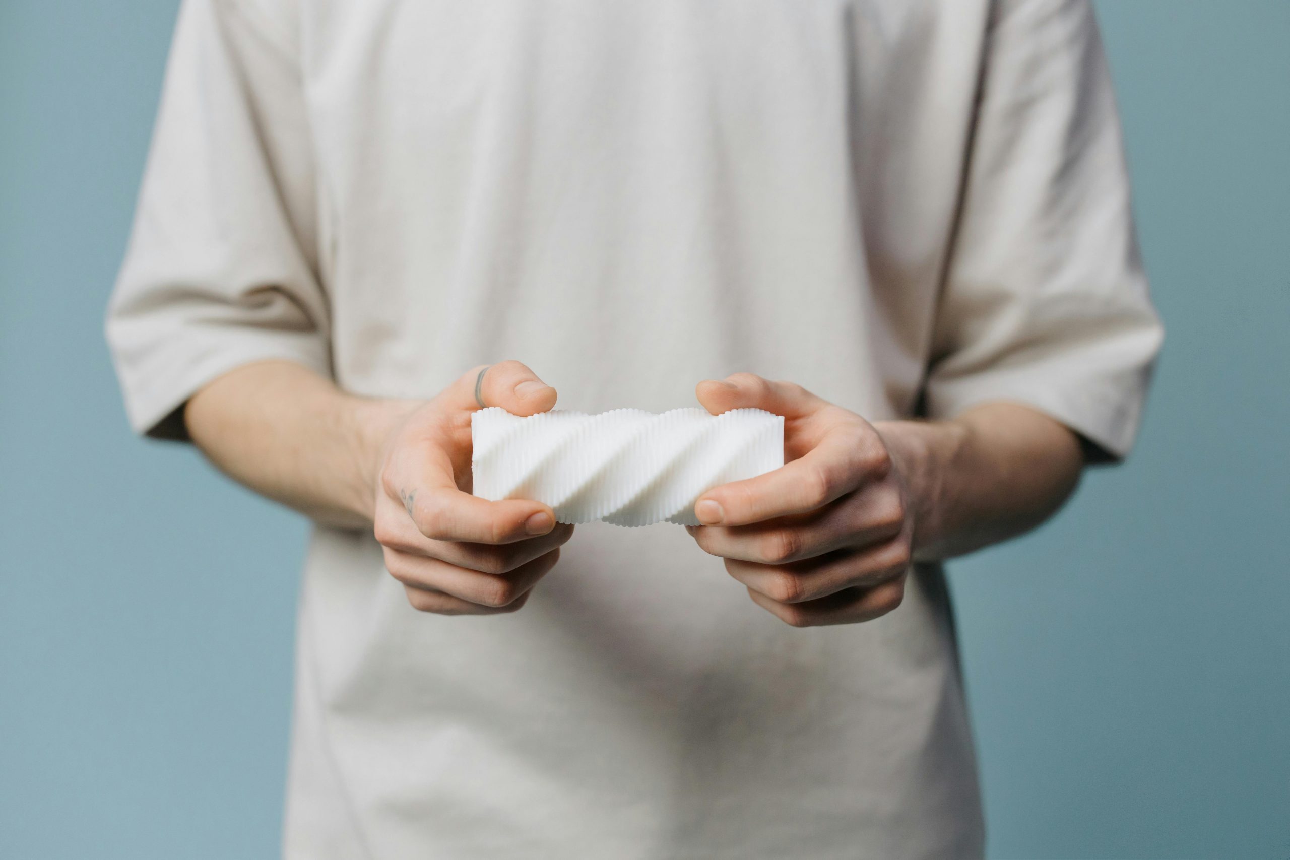 An adult holding a white textured object against a blue background.
